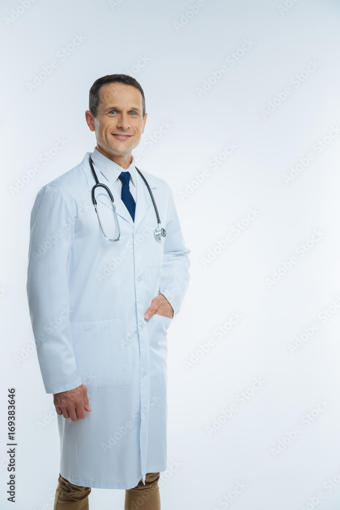 Positive minded mature doctor posing with hand in pocket Positive minded mature doctor posing with hand in pocket