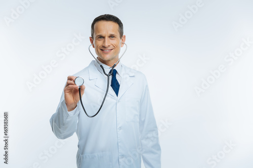 Cheerful male practitioner posing with stethoscope alone