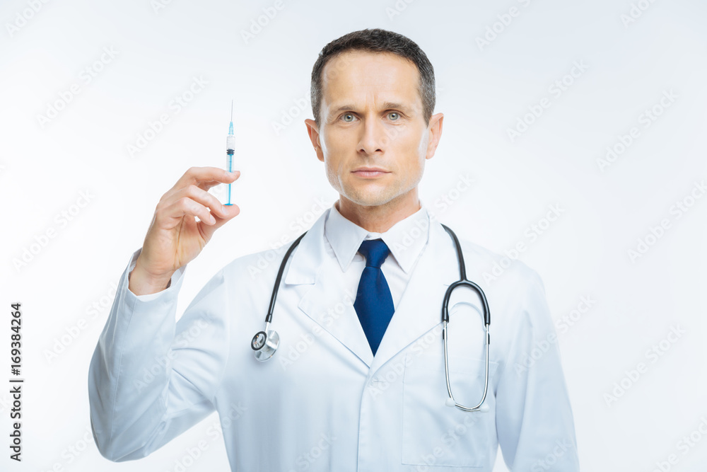 Serious practitioner holding syringe over background Serious practitioner holding syringe over background