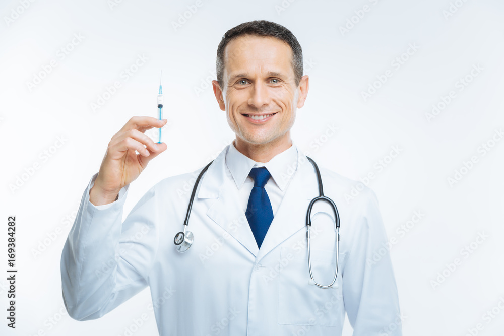 Cheerful doctor posing with syringe for camera Cheerful doctor posing with syringe for camera