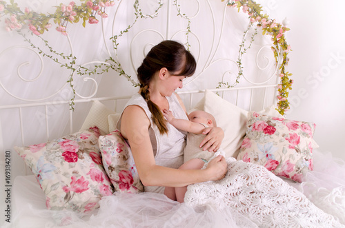 Obraz na płótnie Breastfeeding baby. Young mother holding her newborn child. Mom nursing baby. Woman and new born boy in white bedroom. w salonie