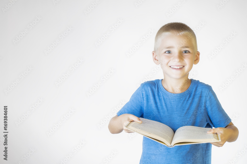 Portrait of little smiling schoolboy with book. Cheerful smiling little kid. Looking at camera. School concept. Portrait of little smiling schoolboy with book. Cheerful smiling little kid. Looking at camera. School concept.