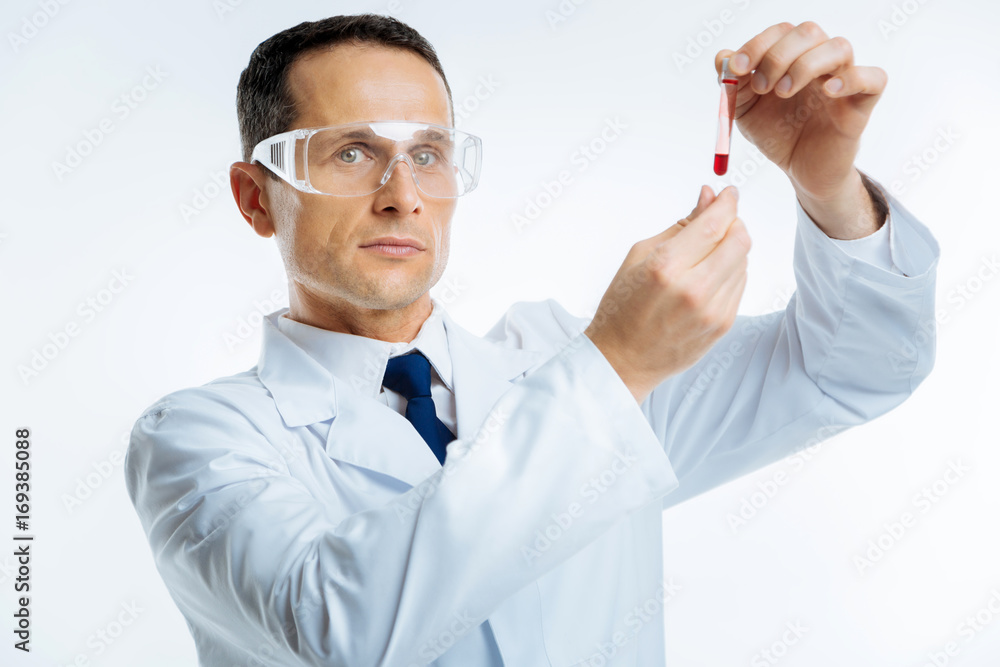 Serious medical scientist with blood sample looking into camera Serious medical scientist with blood sample looking into camera