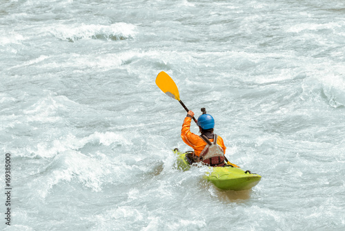 Kayaker paddling in white water rapids,  with copy space