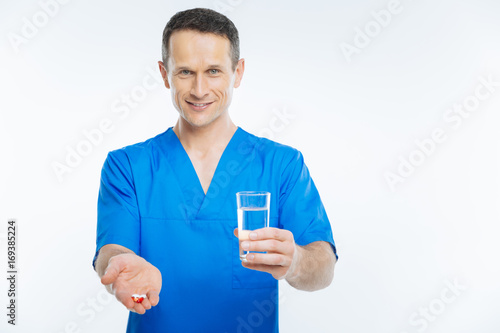 Mindful medical worker posing with water and pills