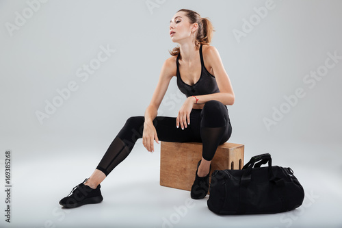 Tired Pretty Sport woman relaxing on box in studio
