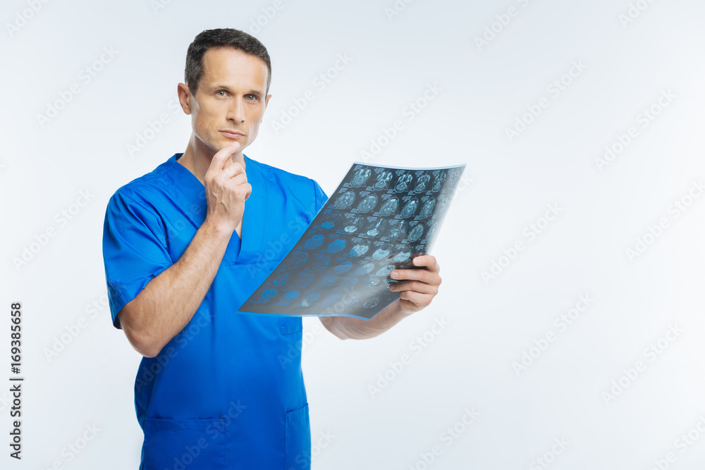 Pensive doctor with x ray scan image looking into camera Pensive doctor with x ray scan image looking into camera