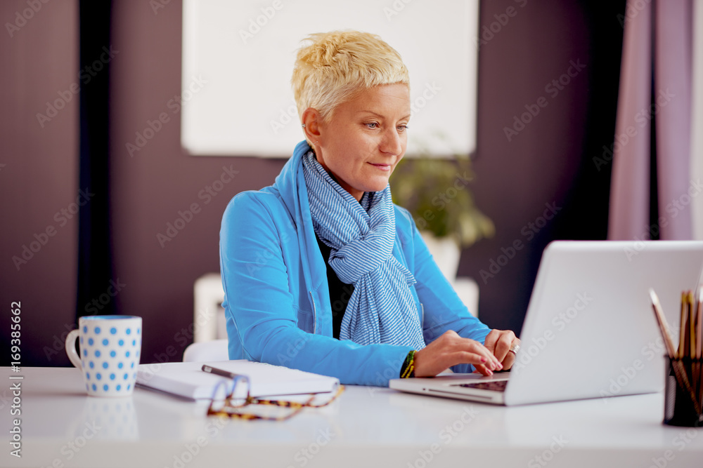 Businesswoman sitting and using laptop computer in modern office Businesswoman sitting and using laptop computer in modern office
