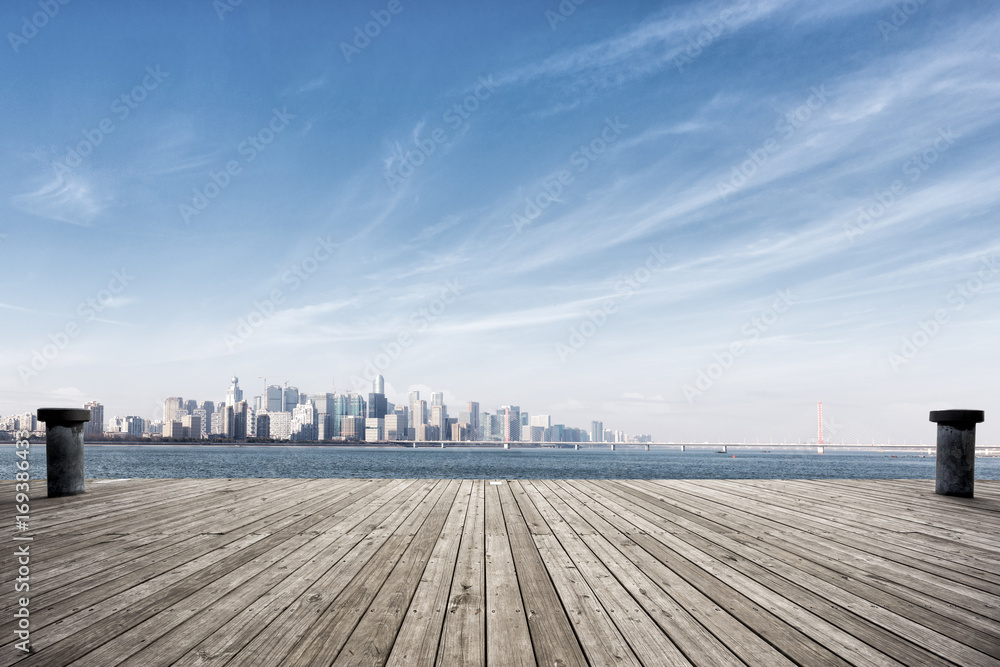 empty wooden floor with cityscape of modern city near water