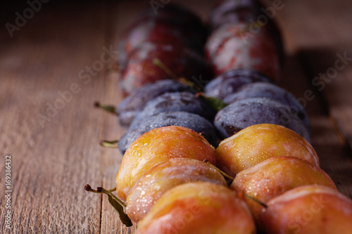 Purple, blue and yellow plums on a wooden table