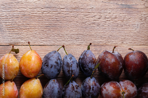 Purple, blue and yellow plums on a wooden table