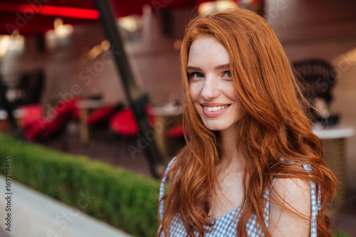 Beautiful young redhead girl with long hair looking at camera photo