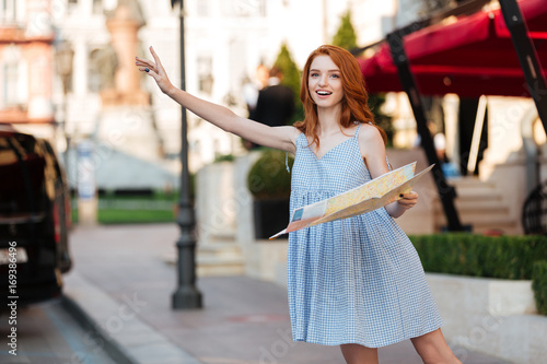 Young pretty girl in dress holding a city guide map