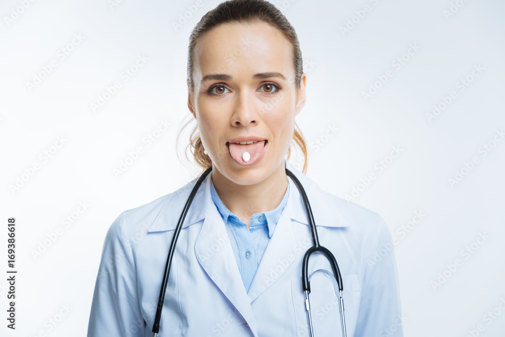 Hazel eyed doctor holding pill on her tongue Hazel eyed doctor holding pill on her tongue