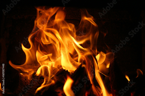 Fire burning inside a brick stove - wood, ash, flames.