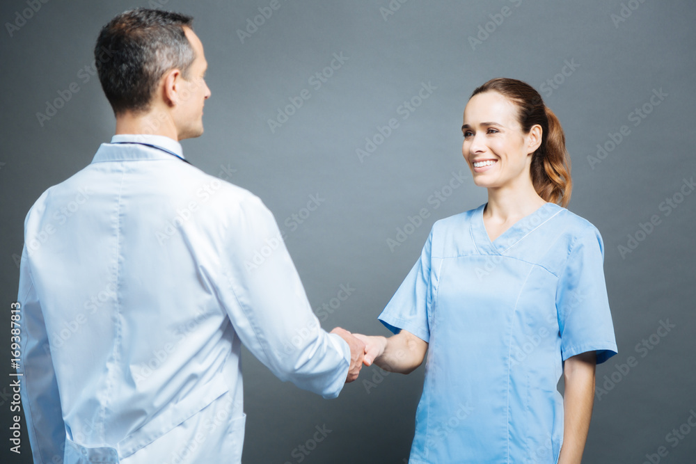 Friendly female doctor shaking hands with male colleagues Friendly female doctor shaking hands with male colleagues