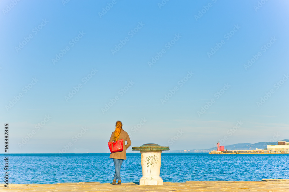 young woman standing lonely in pier at sunset meditating with calm sea
