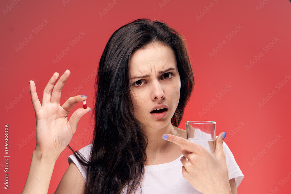 Young woman holding a pill and a glass of water Young woman holding a pill and a glass of water