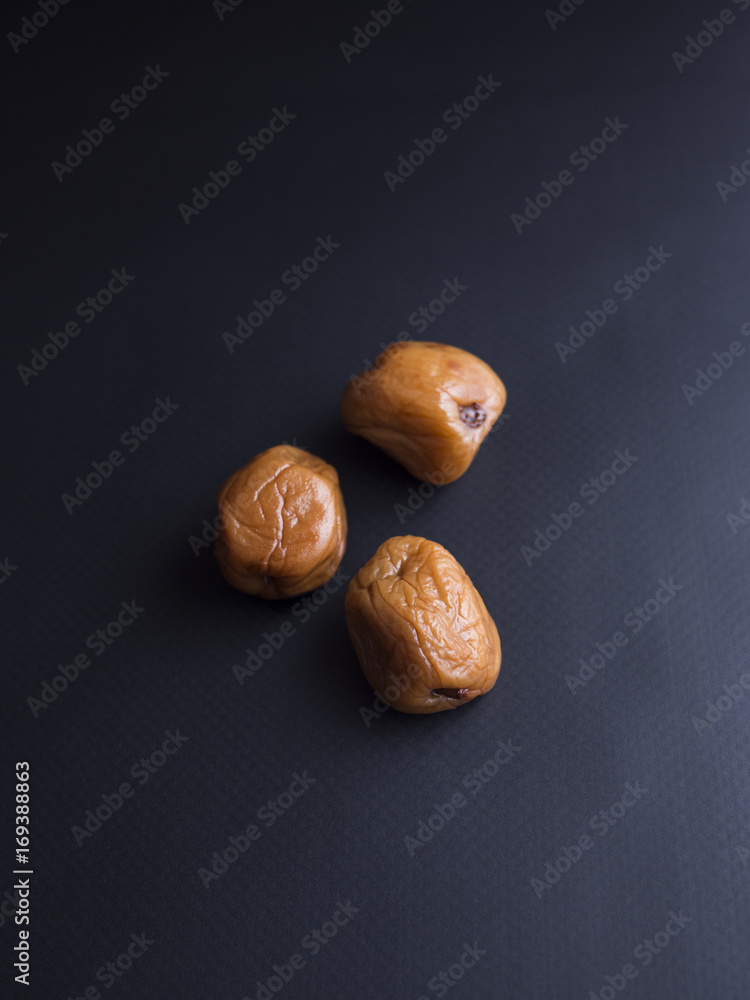 Obraz premium Umeboshi plums from Japan, fermented and salted and placed in a honey syrup. Isolated on black background