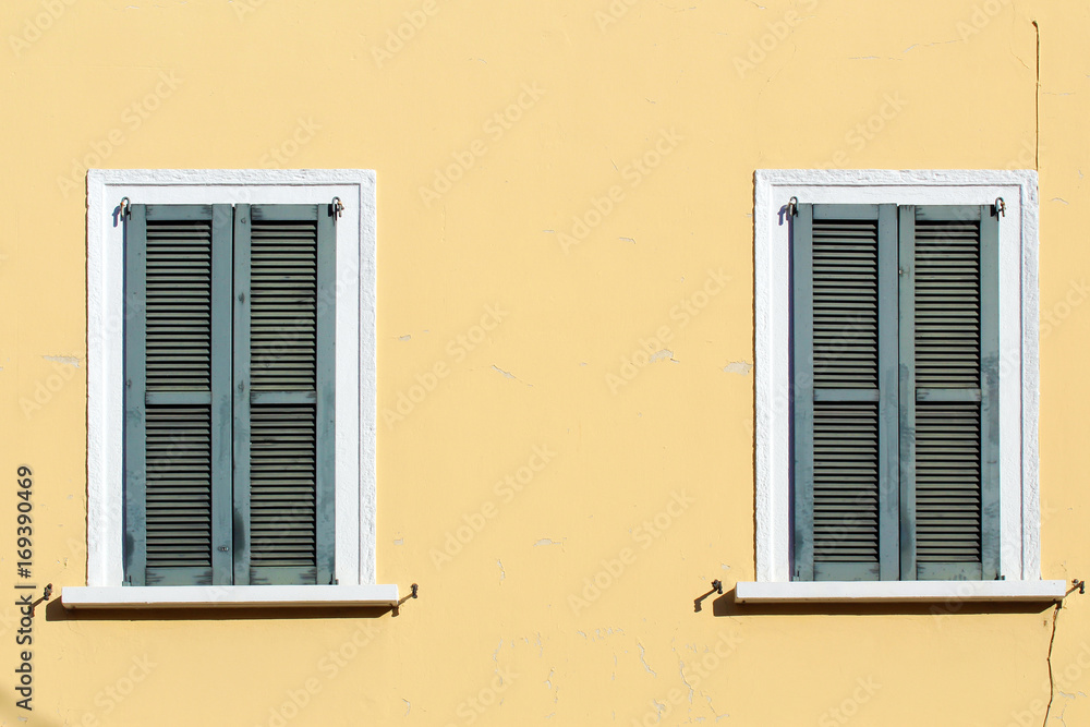 Closed shutter windows on a yellow building Closed shutter windows on a yellow building