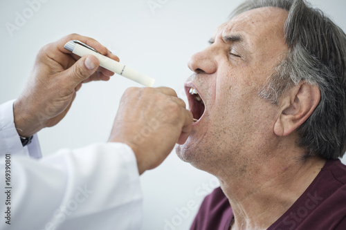 Fototapeta Naklejka Na Ścianę i Meble -  Doctor examines senior man for sore throat