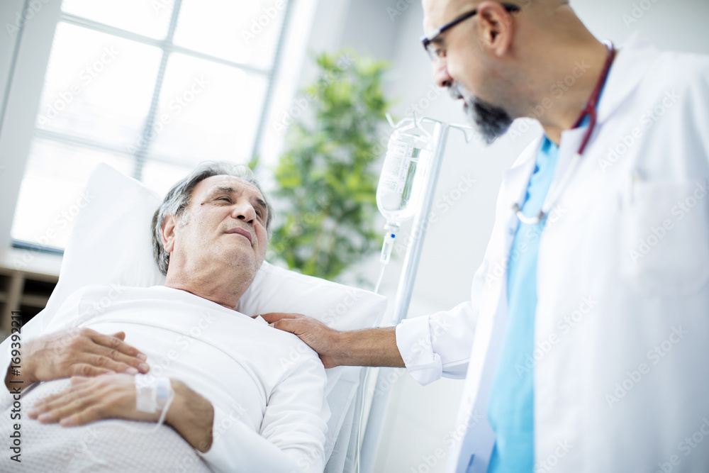 Doctor talking to patient in hospital bed Doctor talking to patient in hospital bed