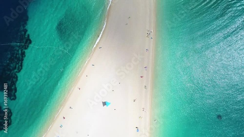 Aerial view of people swimming and sunbathing on Zlatni Rat, on the island of Brac, Croatia. Tilting up the image.