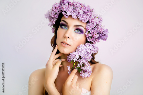 Spring girl. Beautiful model with bright professional make-up and a wreath of fresh flowers in her hair. Juicy summer look. © kassiya