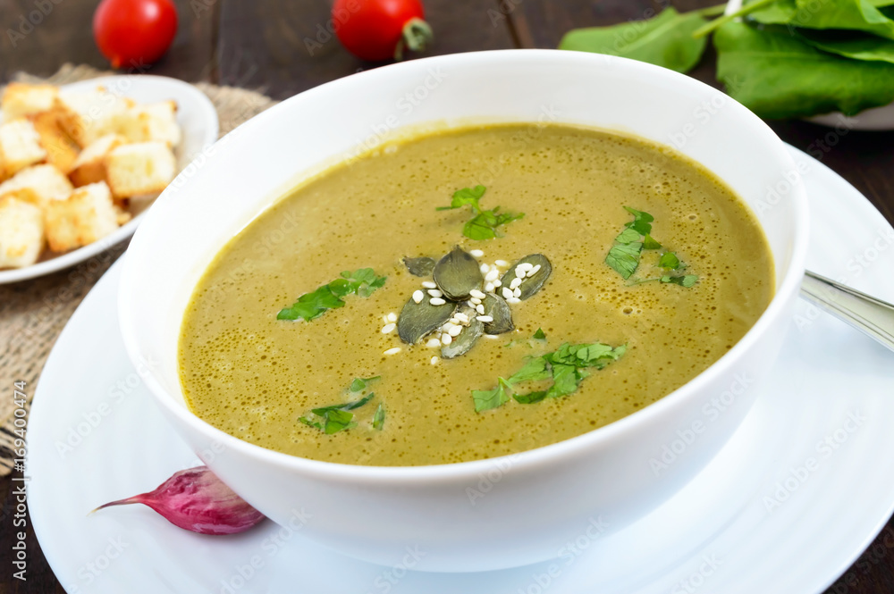 Vegetable cream soup with spinach and potatoes in a white bowl with garlic croutons on a dark wooden background. Dietary vegetarian menu. Proper nutrition. Vegetable cream soup with spinach and potatoes in a white bowl with garlic croutons on a dark wooden background. Dietary vegetarian menu. Proper nutrition.