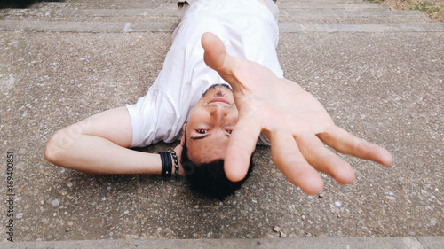 Hombre joven tumbado en el suelo extendiendo la mano para tocar a alguien