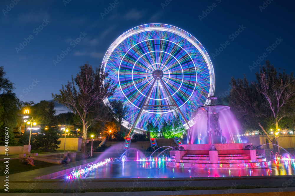 city Ferris wheel with a fountain in the evening in the Park