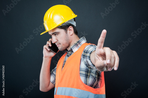 Constructor wearing equipment talking on phone making hold gesture