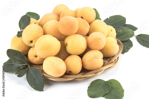 fresh apricots on a white background with leaves and a basket