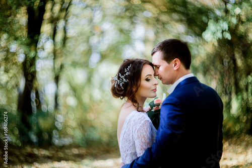 Blurred picture of tall groom hugging bride tender in the forest © IVASHstudio