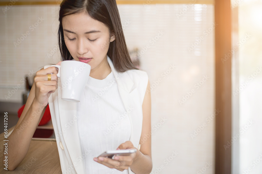 Smiling Asian girl with a cup of coffee sitting in cafe