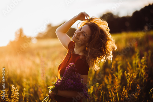 Woman in red dress whirls in the rays of evening sun