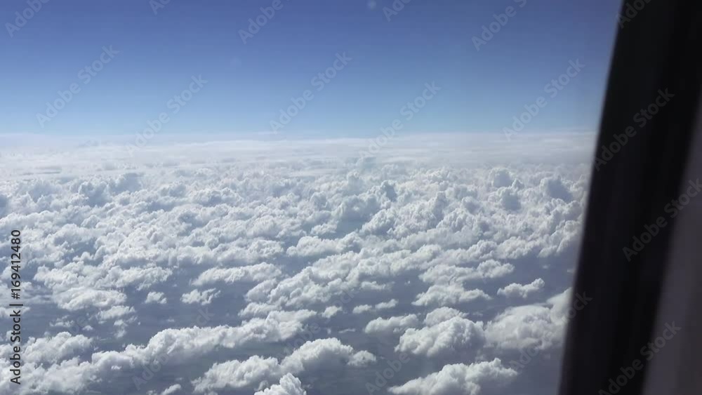 Flying over the clouds. View from plane aircraft passenger window. Clouds and skyline horizon panoramic view. Flying over the clouds. View from plane aircraft passenger window. Clouds and skyline horizon panoramic view.