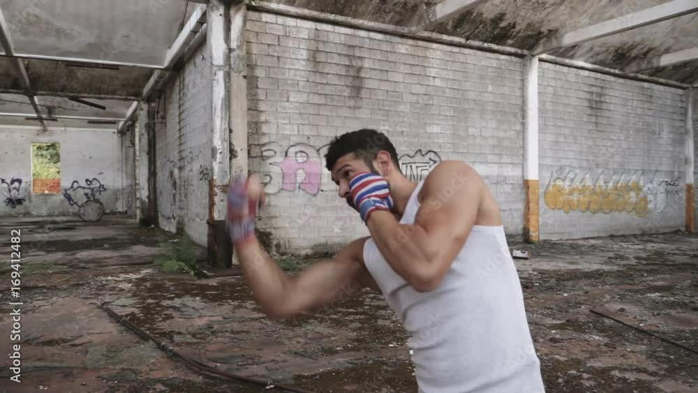 Muscular male boxer doing shadow boxing exercise in an old abandoned building. Muscular male boxer doing shadow boxing exercise in an old abandoned building.
