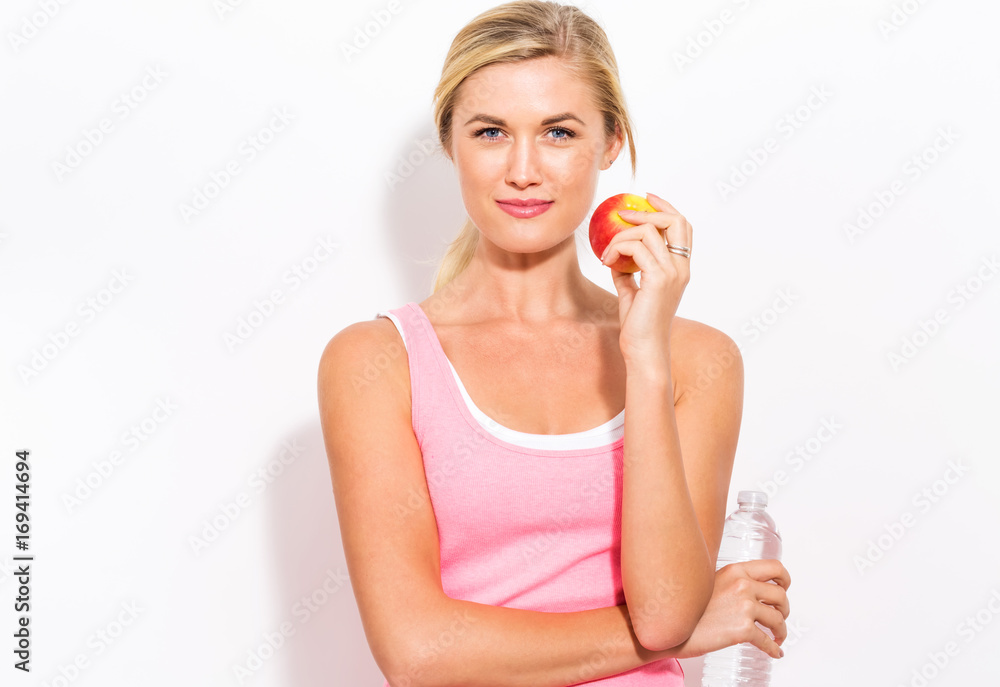 Happy young woman holding an apple and a water bottle Happy young woman holding an apple and a water bottle