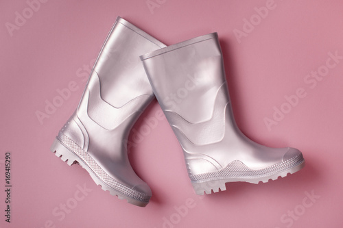 Autumn creative background: stylish silver marching rain boots on pink background. Top view. Flat lay.