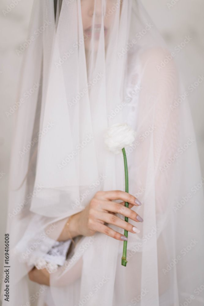 Obraz premium Beautiful girl bride holding a white flower, Ranunculus, close-up