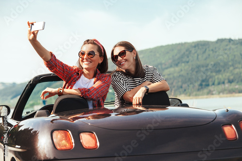 Cuadro en lienzo Two female freinds take selfie photo in cabriolet car with beautiful mountain la