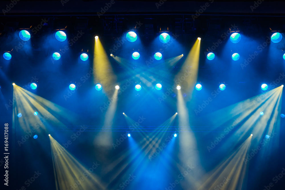 Wall murals Lighting equipment on the stage of the theatre during the  performance. The light rays from the spotlight through the smoke. Blue and  yellow rays of light. - Nikkel-Art.co.uk