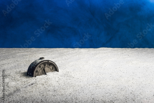 An old alarm clock on white sand and blue background
