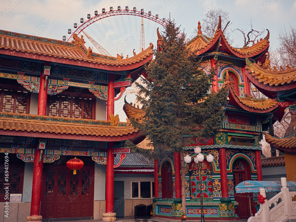Naklejka premium beautiful Buddhist temple with a tree in the middle. Background is a huge ferris wheel