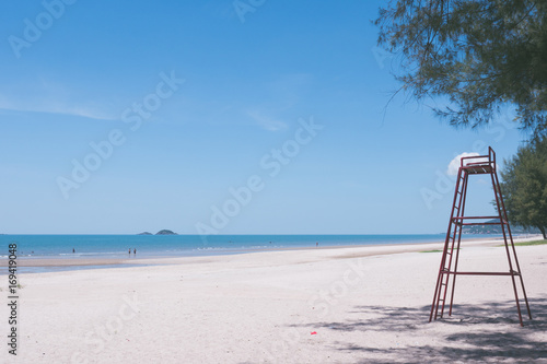 Beautiful beach with blue sky and a tall red lifeguard chair.