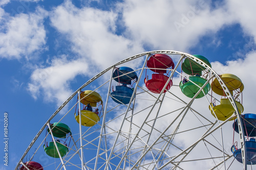 colorful ferris wheel against blue sky with clouds