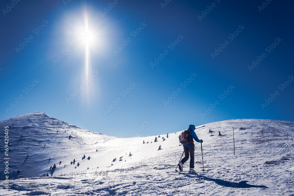 Skialpinist in beautiful winter landscape with sun, Tourist on trip in mountains, Winter sport for one, Background winter sport, Symbol of winter sports in mountains, Skialpinist on snowy mountains