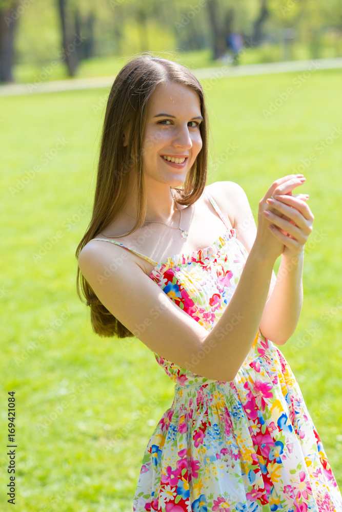 Portrait of young beautiful woman with long hair wearing flower dress in green spring park Portrait of young beautiful woman with long hair wearing flower dress in green spring park