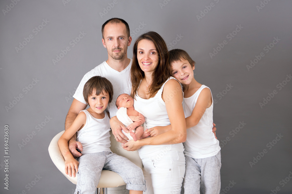 Beautiful family portrait, father, mother and three boys, looking happily at camera